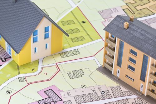 Condominium versus detached house - concept with single-family house, apartment building, imaginary cadastral map and General Urban Planning